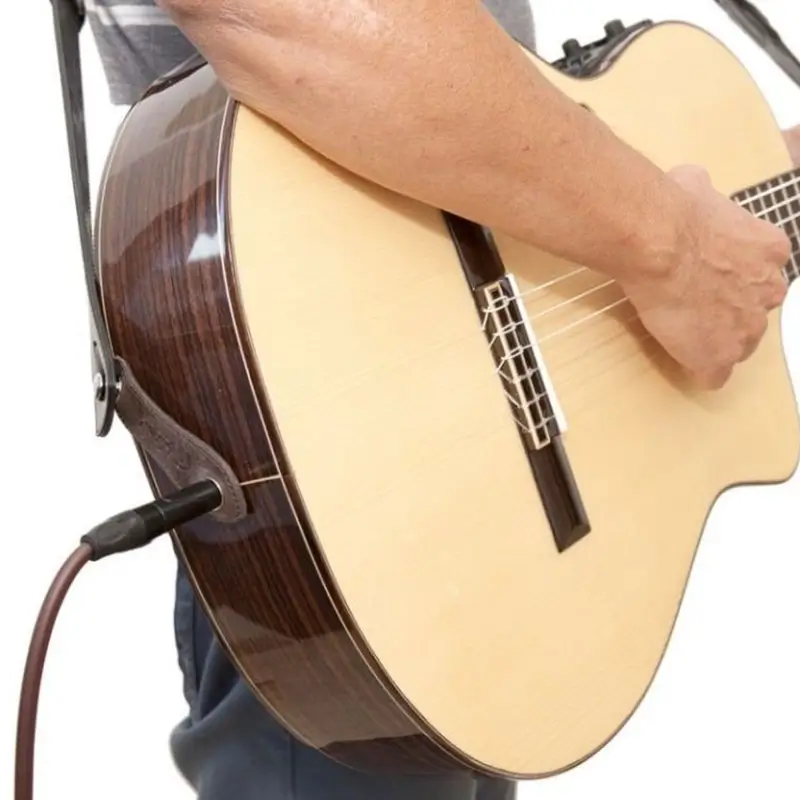 homem segurando violão e mostrando o conector p10 com um cabo p10 conectado