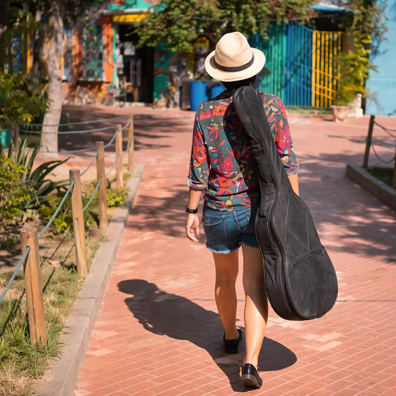 pessoa caminhando com a bag de violao (capa) na rua