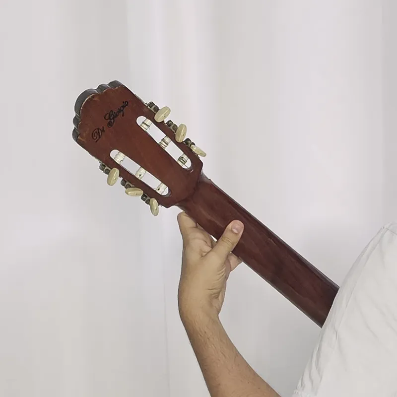 mão esquerda com polegar por detrás do braço do violão
