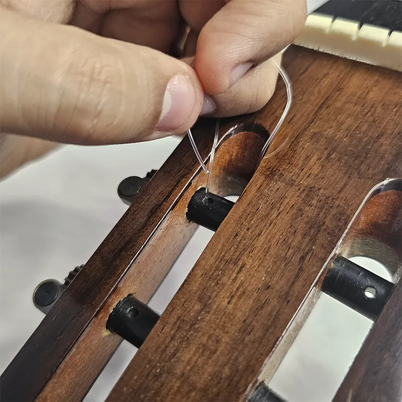 reinserindo corda mais aguda no buraco do pino da tarraxa para travar a corda
