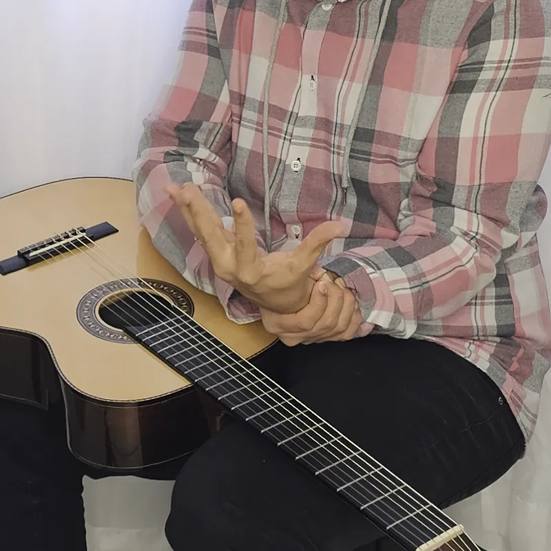 Pessoa com dor na mão após tocar o violão