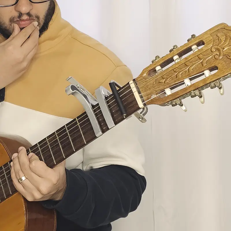 Pessoa pensando como funciona o capotraste com varios capotrastes no braço do violão